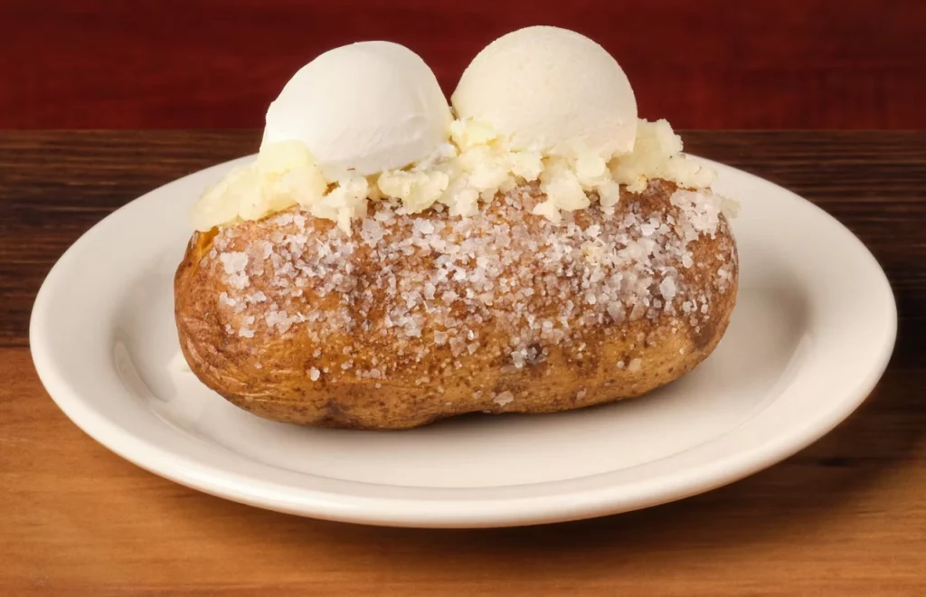 Plate containing baked potato with creamy white topping