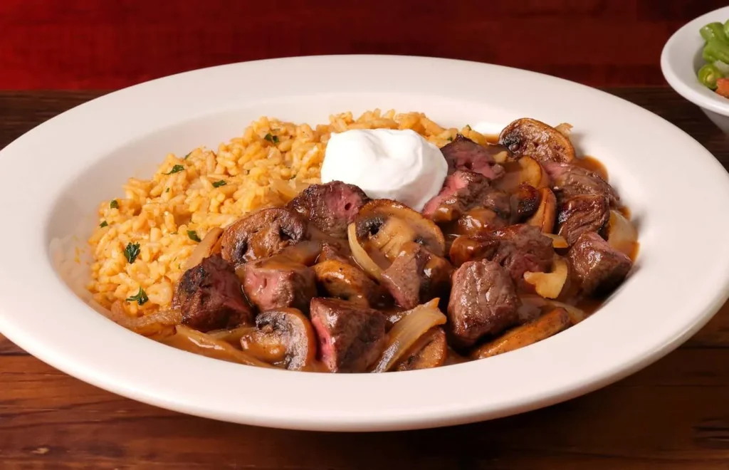 beef tips with seasoned rice and sour cream on the top