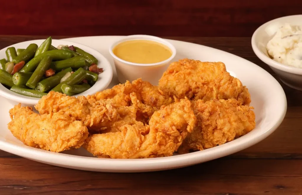 brown crispy chicken critters served with sauce and green beans on the side 