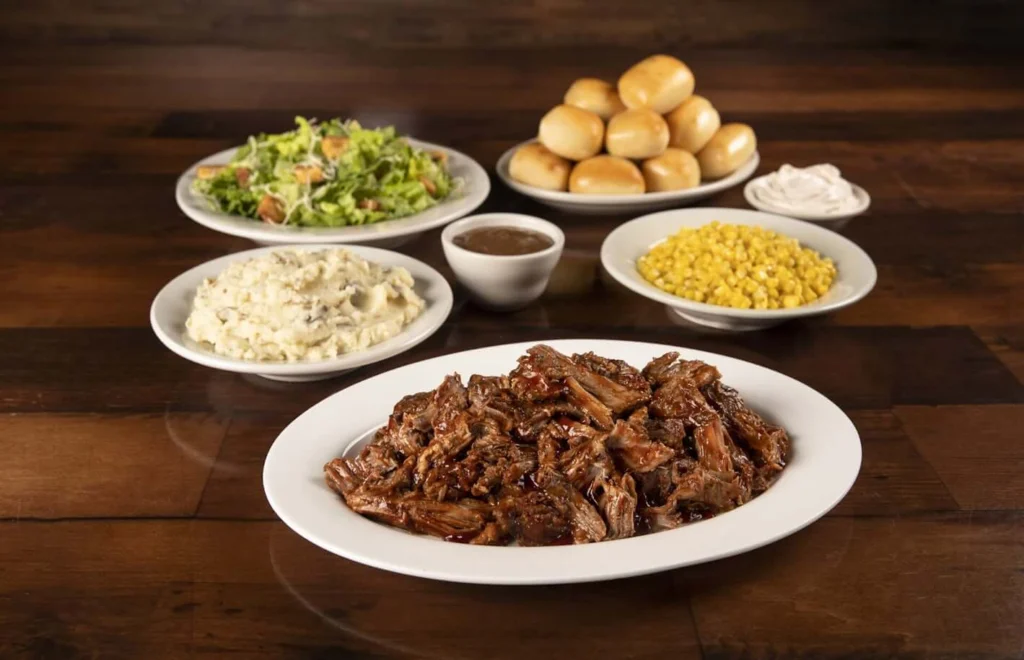 Family-sized pulled pork served with baked breads, mashed potatoes, buttered corn, salad and sour cream