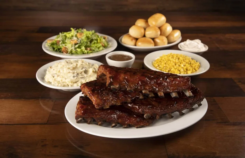 Family-sized ribs serve with baked breads, green salad, buttered corn and mashed potatoes