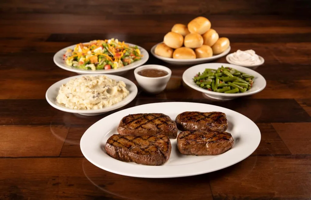 Family-sized sirloin platter with green beans, mashed potatoes, salad, and baked breads