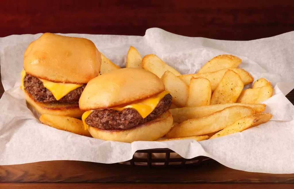 2 mini cheeseburgers served with crispy fries in a basket