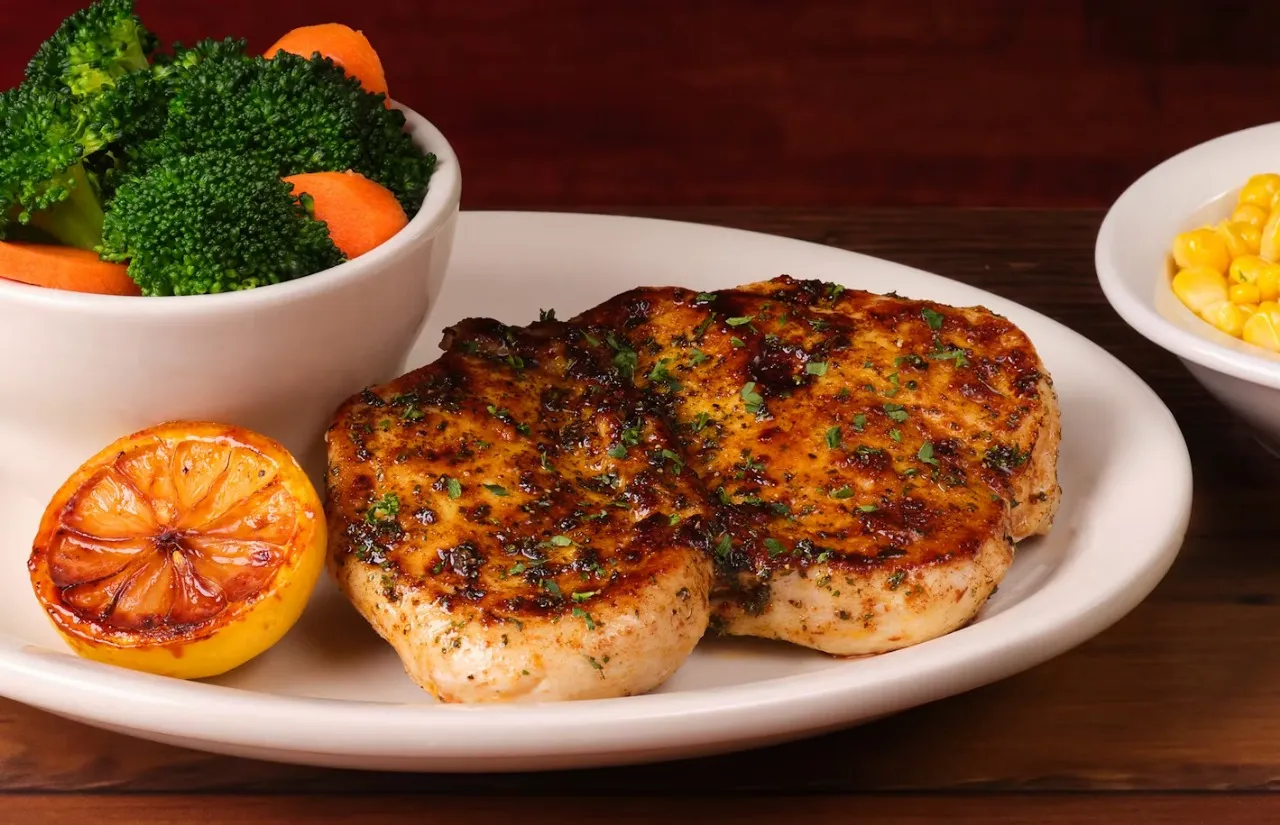 Herb-crusted chicken with steamed vegetables and lemon served on side